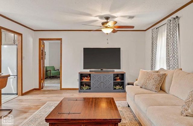 living area with a ceiling fan, visible vents, crown molding, and light wood finished floors