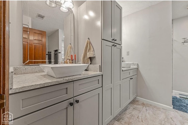 700 Oak Hollow Ln, Jonesboro, AR 72401 - bathroom featuring double vanity, marble finish flooring, a textured ceiling, and baseboards