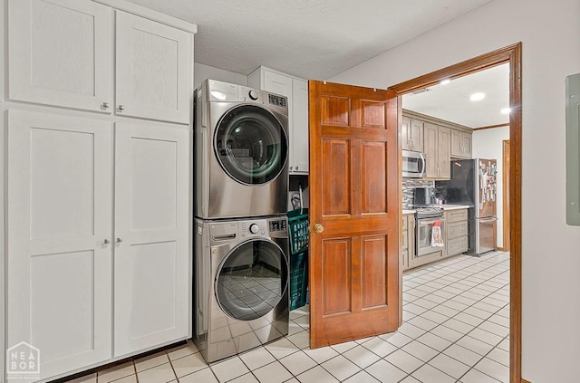 laundry area featuring light tile patterned flooring, stacked washer and clothes dryer, and cabinet space