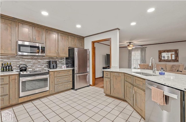 kitchen featuring a sink, tasteful backsplash, open floor plan, ceiling fan, and appliances with stainless steel finishes