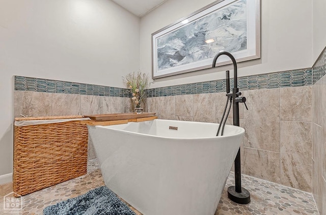full bathroom featuring tile walls, a freestanding tub, a wainscoted wall, and tile patterned floors