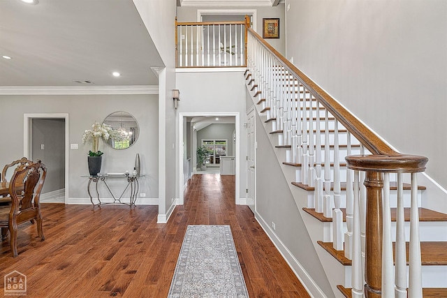 foyer featuring ornamental molding, stairs, wood finished floors, baseboards, and recessed lighting