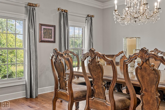 dining area featuring baseboards, light wood-style floors, a chandelier, healthy amount of natural light, and crown molding