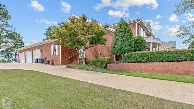 view of side of home with brick siding, a lawn, driveway, central AC, and an attached garage
