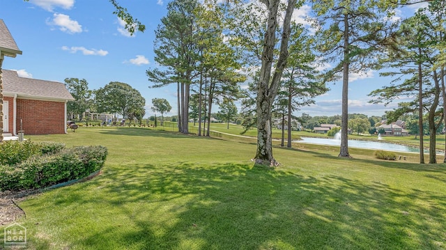 view of green lawn with a water view