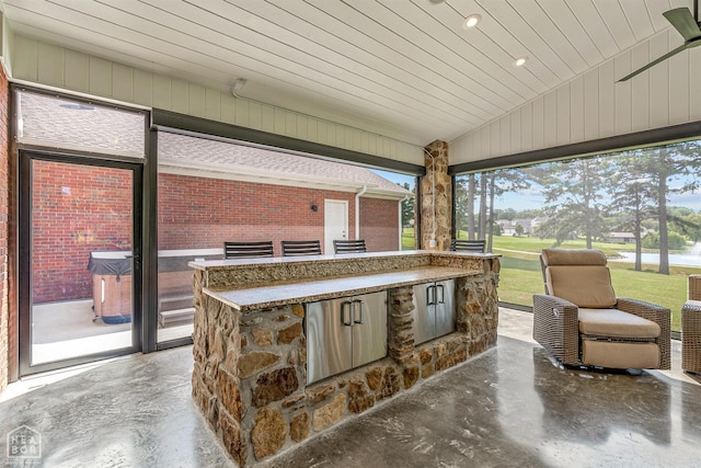 view of patio featuring exterior bar, an outdoor kitchen, and a water view