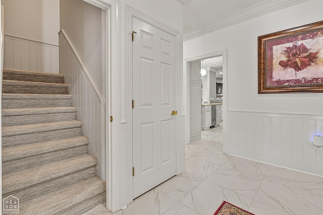 stairway featuring marble finish floors, wainscoting, a decorative wall, and ornamental molding