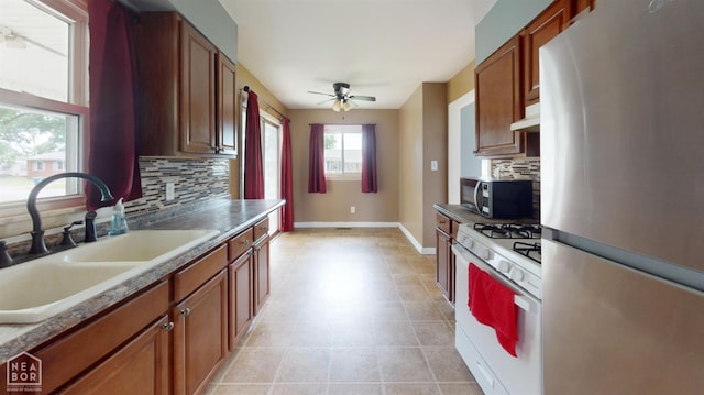 207 11th St, Marked Tree, AR 72365 - kitchen with appliances with stainless steel finishes, ceiling fan, tasteful backsplash, under cabinet range hood, and brown cabinetry