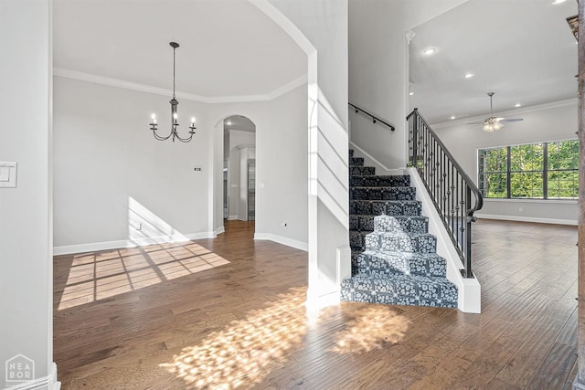interior space with arched walkways, ceiling fan with notable chandelier, crown molding, and wood finished floors