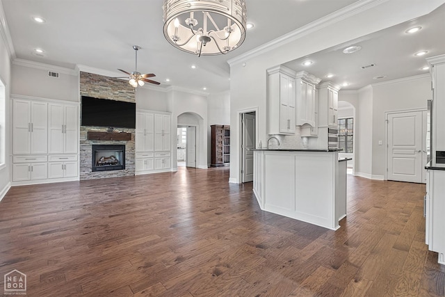 unfurnished living room featuring arched walkways, visible vents, ceiling fan with notable chandelier, and dark wood finished floors