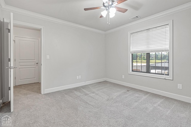 spare room featuring visible vents, baseboards, ornamental molding, a ceiling fan, and carpet