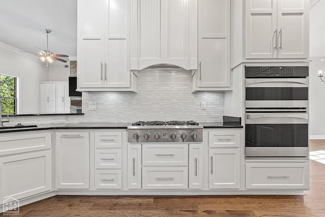 kitchen with tasteful backsplash, dark wood-style flooring, white cabinetry, ceiling fan, and appliances with stainless steel finishes