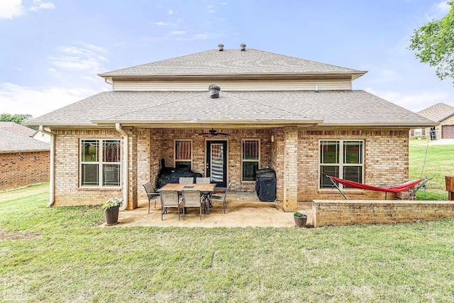 back of house featuring a patio area, brick siding, a lawn, and roof with shingles