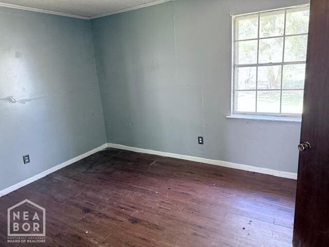 unfurnished room with crown molding, wood finished floors, and baseboards