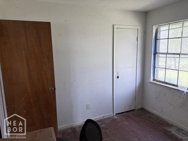 unfurnished bedroom with wood finished floors and multiple windows
