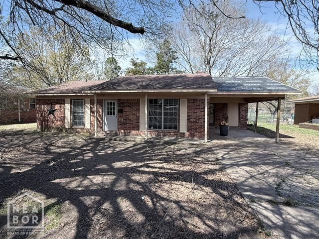 view of front of house featuring concrete driveway, an attached carport, and brick siding