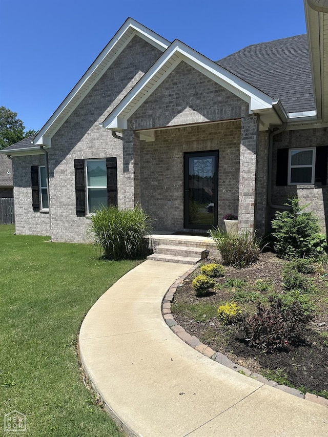 105 Brayden Ln, Brookland, AR 72417 - view of exterior entry featuring a lawn, brick siding, and roof with shingles