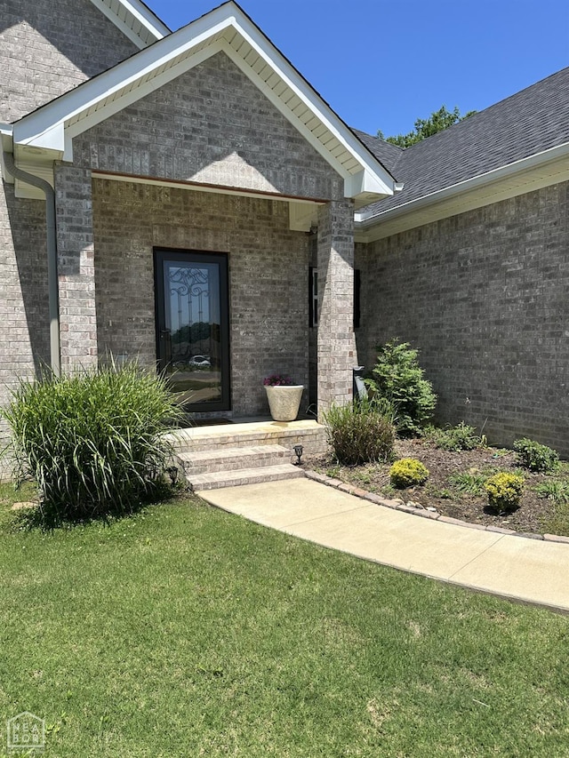 105 Brayden Ln, Brookland, AR 72417 - view of exterior entry with brick siding and a lawn