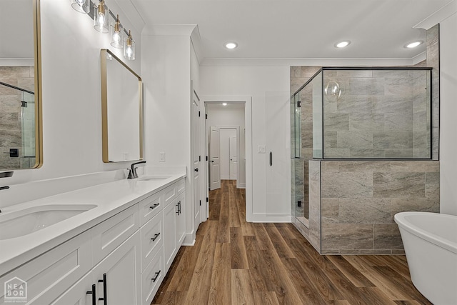3425 Hudson Ct, Jonesboro, AR 72405 - bathroom featuring double vanity, a shower stall, a soaking tub, wood finished floors, and crown molding