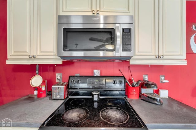 316 SE 2nd St SE, Walnut Ridge, AR 72476 - kitchen featuring stainless steel microwave, black range with electric stovetop, cream cabinets, and dark countertops