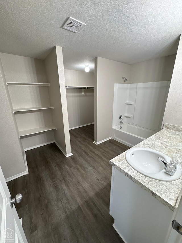 3726 Glitterman Dr, Jonesboro, AR 72404 - bathroom featuring wood finished floors, vanity, bathing tub / shower combination, baseboards, and a textured ceiling