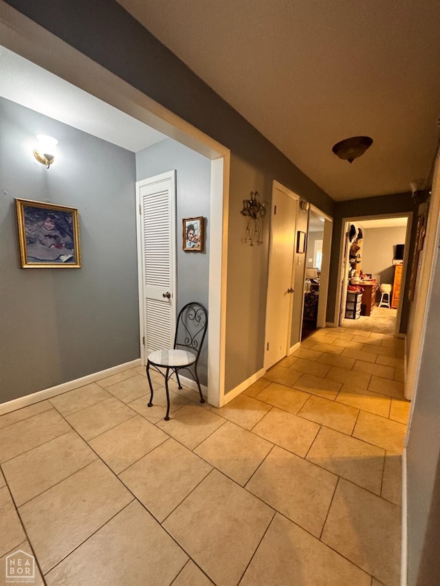 hallway with light tile patterned floors and baseboards
