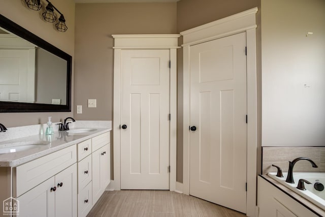 full bathroom with double vanity, a sink, and a bath