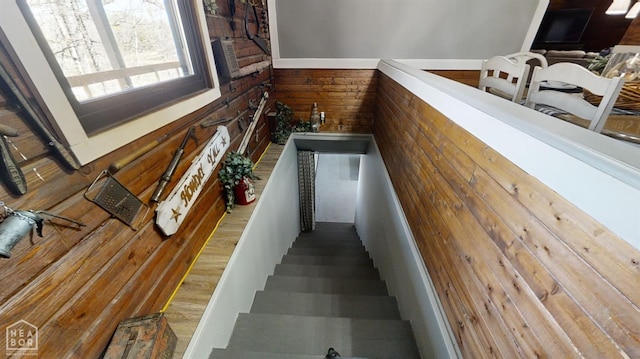 stairway featuring wooden walls