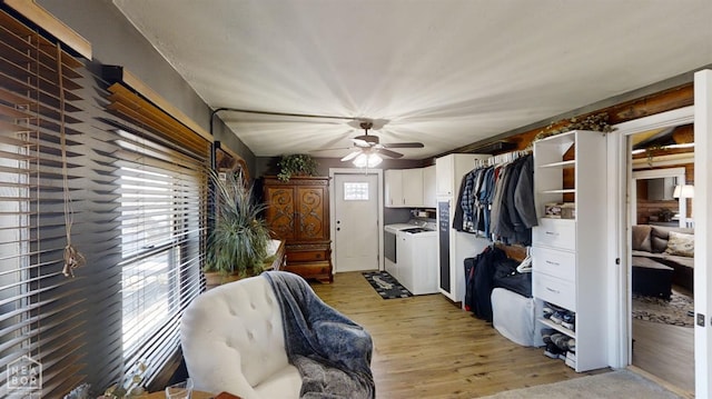 interior space with light wood-style floors, independent washer and dryer, open shelves, a ceiling fan, and white cabinets