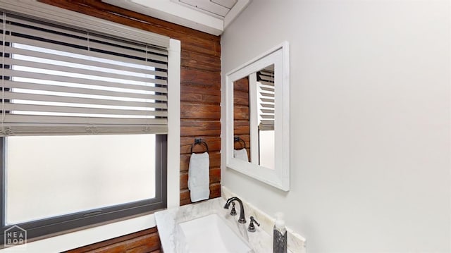 bathroom featuring wood walls and a sink