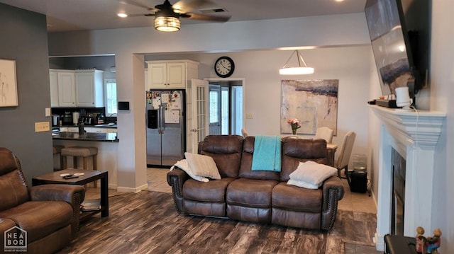 living area featuring a fireplace, a ceiling fan, dark wood-style floors, and visible vents