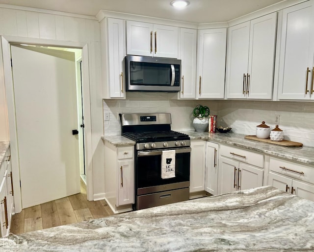 104 N Hunter Ln N, Jonesboro, AR 72405 - kitchen with stainless steel appliances, light wood-style floors, tasteful backsplash, and white cabinets