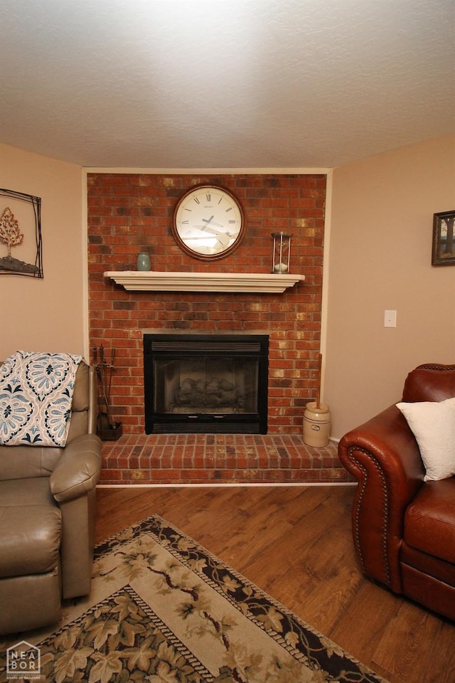 living room with a brick fireplace and wood finished floors