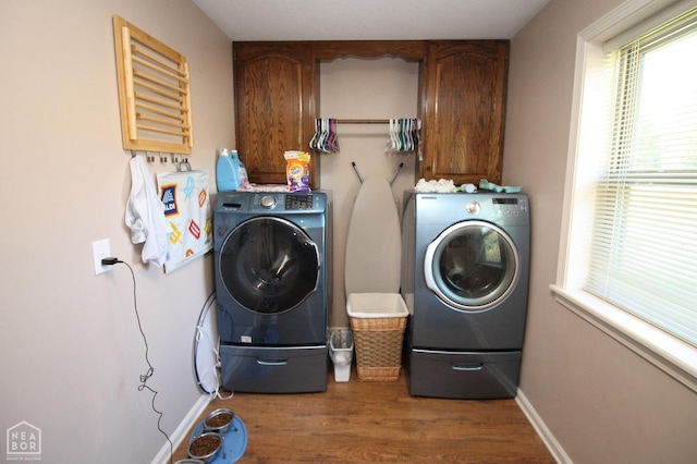 laundry room with cabinet space, baseboards, washing machine and dryer, and wood finished floors