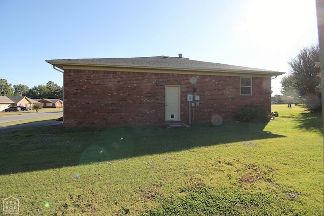 rear view of house featuring a yard and brick siding