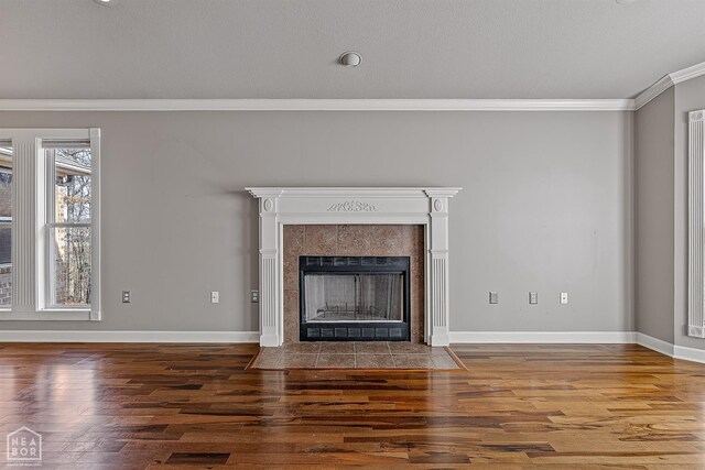 2101 Belleview Cv, Jonesboro, AR 72404 - unfurnished living room with crown molding, wood finished floors, a tiled fireplace, and baseboards
