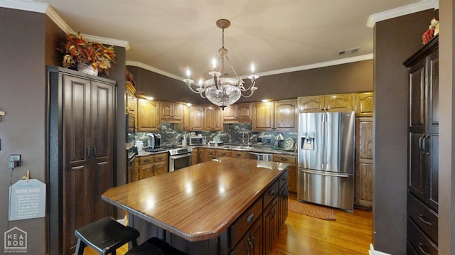 3102 Sara Creek Dr, Jonesboro, AR 72401 - kitchen with appliances with stainless steel finishes, backsplash, a chandelier, light wood-type flooring, and decorative light fixtures