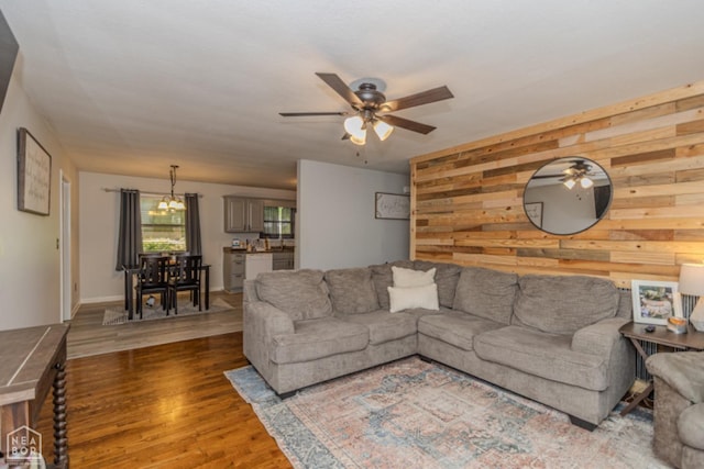 living room with wooden walls, ceiling fan, and wood finished floors