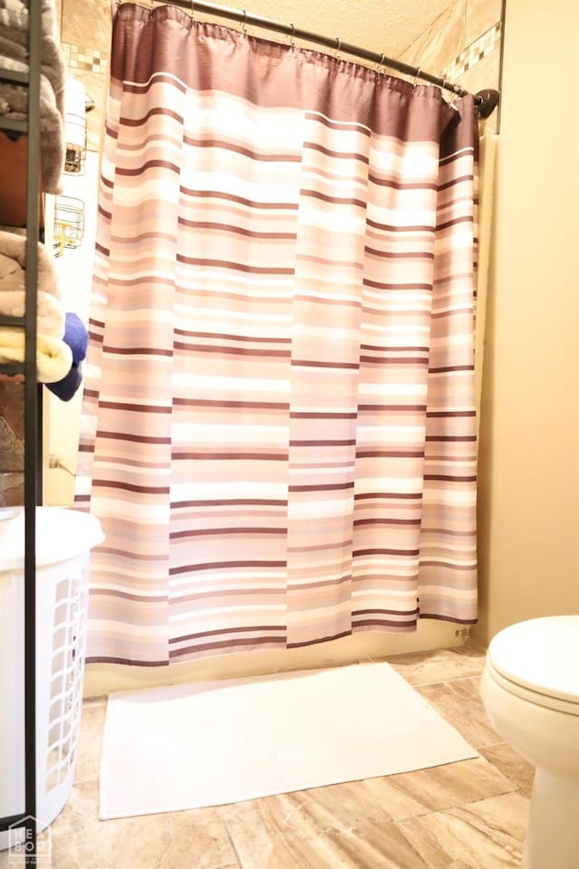 bathroom with toilet and a shower with curtain
