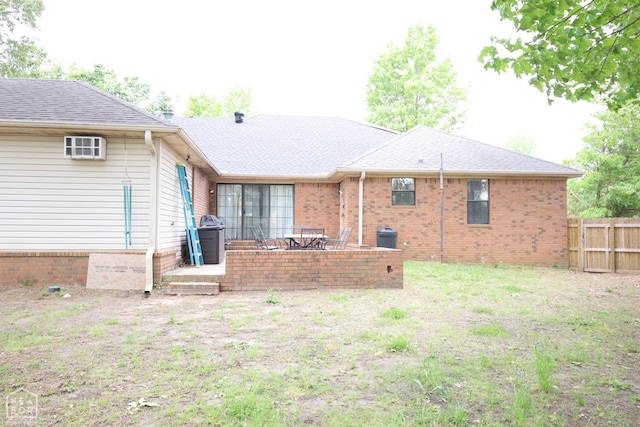 back of property featuring brick siding, fence, a patio, and roof with shingles