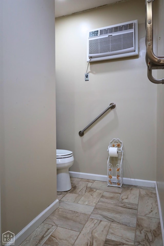 bathroom with toilet, baseboards, marble finish floor, and a wall mounted air conditioner