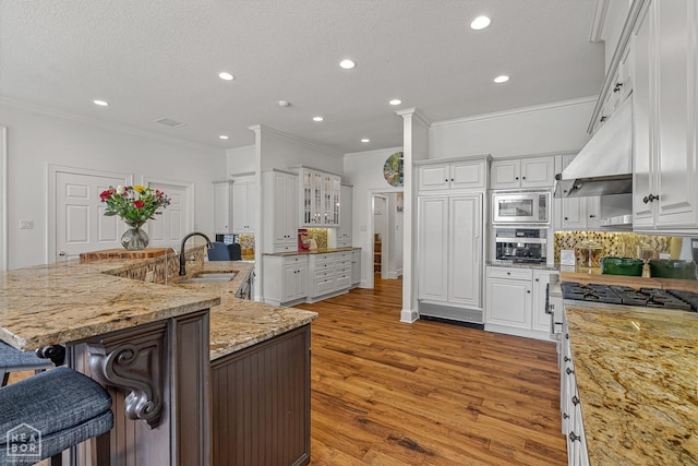 3500 Big Creek Cv, Jonesboro, AR 72404 - kitchen featuring appliances with stainless steel finishes, ornamental molding, white cabinets, a kitchen bar, and recessed lighting