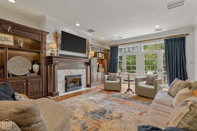 3500 Big Creek Cv, Jonesboro, AR 72404 - living room featuring ornamental molding, french doors, a textured ceiling, a fireplace, and wood finished floors