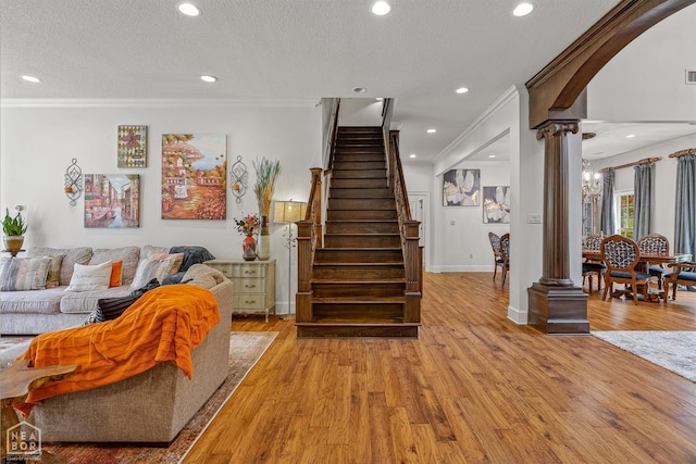3500 Big Creek Cv, Jonesboro, AR 72404 - living room featuring decorative columns, ornamental molding, light wood finished floors, a textured ceiling, and arched walkways