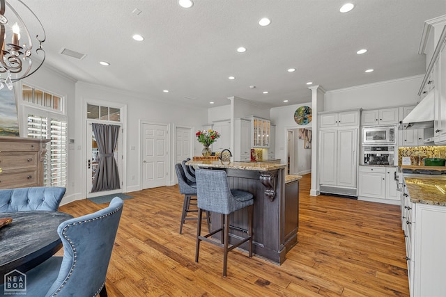 3500 Big Creek Cv, Jonesboro, AR 72404 - kitchen featuring stainless steel microwave, crown molding, recessed lighting, a breakfast bar, and white cabinets