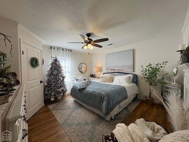 bedroom with a textured ceiling, a ceiling fan, ornamental molding, visible vents, and wood finished floors