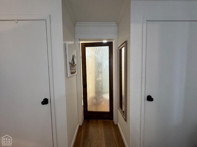hall with dark wood-style flooring, baseboards, and ornamental molding