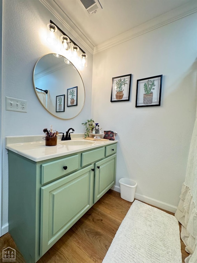 bathroom with vanity, baseboards, crown molding, visible vents, and wood finished floors