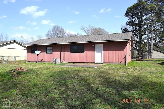 rear view of property with central AC unit, fence, and a lawn