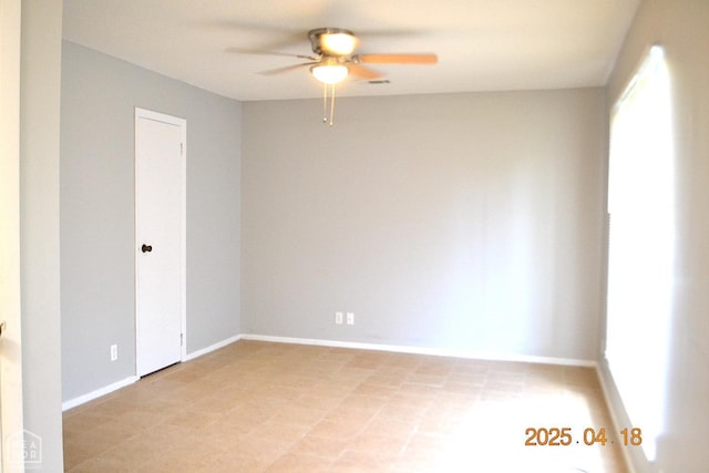 spare room featuring visible vents, ceiling fan, and baseboards